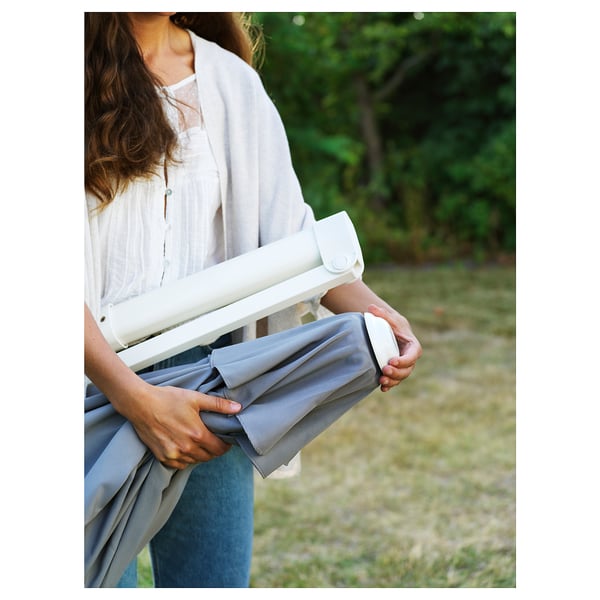 Person holds grey fabric device outdoors. Product: HÖGÖN parasol, machines washable, uv protective.