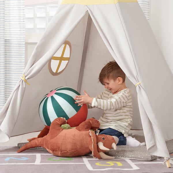 Boy in tent with ball and toy mammoth.