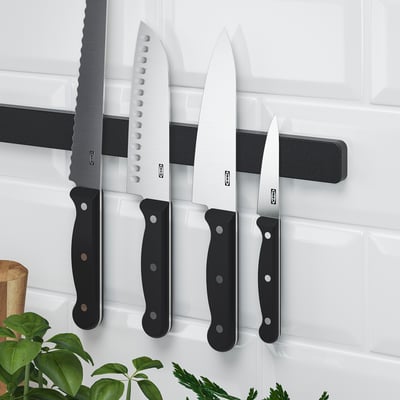 Magnetic knife rack on wall holding several knives, freeing workspace.