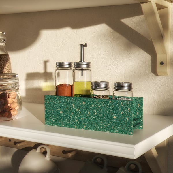 Green speckled spice rack with glass jars on kitchen shelf.