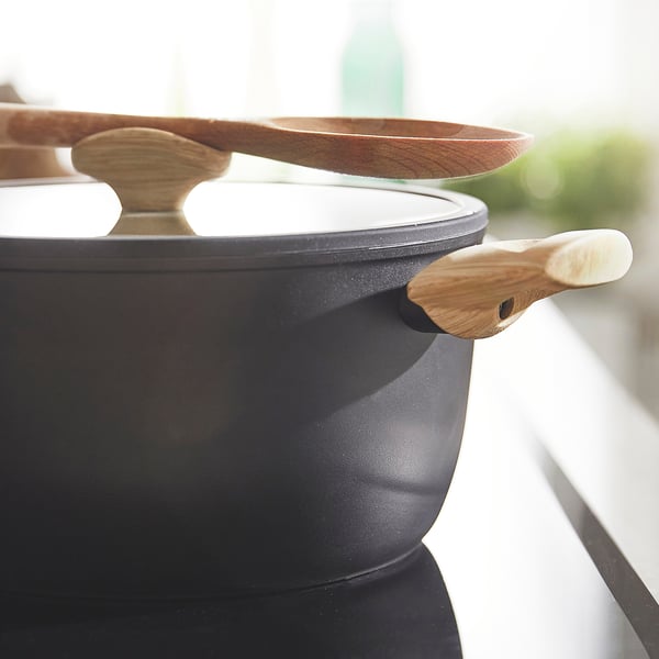 Black saucepan with wooden handle, lid, and spoon. Ideal for non-stick cooking, easy to clean and lift.