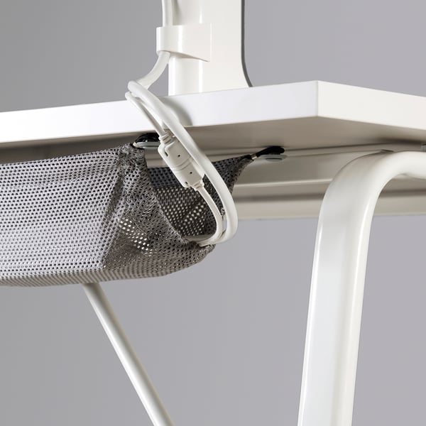 White desk with mesh storage and cable clips.