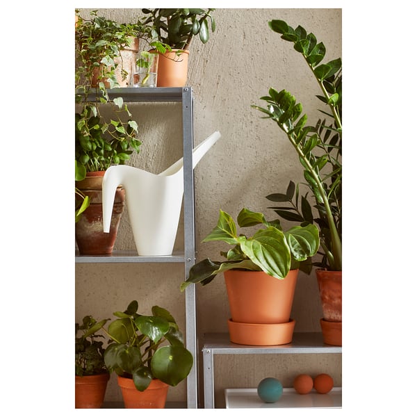Metal shelving unit with terracotta pots, plants, and white pitcher.