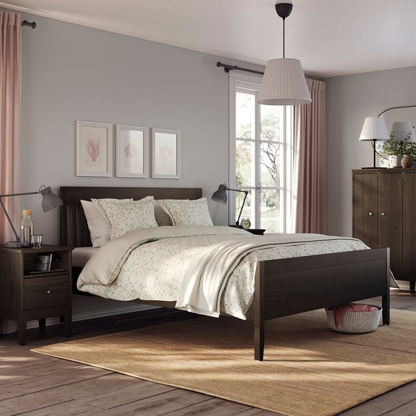 Modern bedroom with IDANÄS dark wood bed, white linens, pink accents, night lamps, artwork, and a large window.