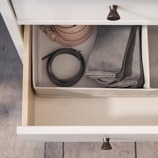 IDANÄS drawer in white pine stores folded grey jumper and rolled leather belts neatly.