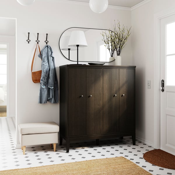 Elegant entryway with IDANÄS dark wood cabinet, mirror, hooks, lamp, vase, stool, and geometric rug.