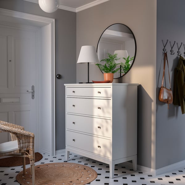 Bright entryway with white IDANÄS chest, black mirror, lamp, and coat hooks, grey walls, and black-and-white tiles.