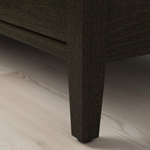 Dark wooden table leg on light wooden floor. High-quality finish, robust design.