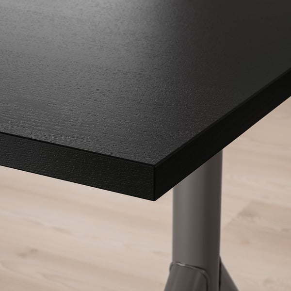 Close-up of sleek, black tabletop with smooth, even surface, supported by sturdy metal legs.