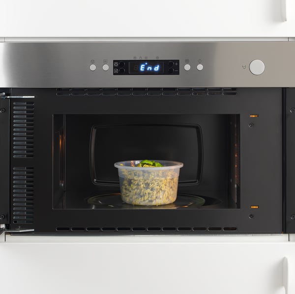 Modern microwave with digital display and a bowl of food inside.