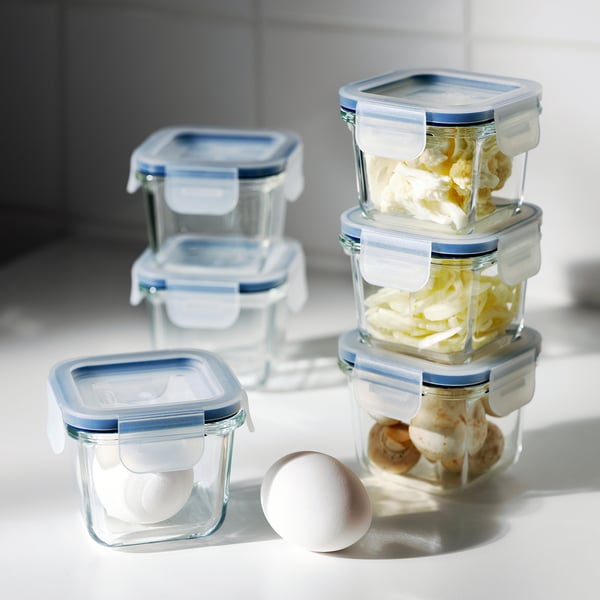 Stacked glass food containers with blue lids store food, prevent spills, and allow visibility of contents.