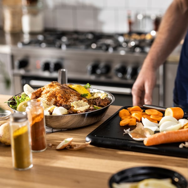 Wooden counter with cooked food, prepped veggies, and grater; oven blurred.
