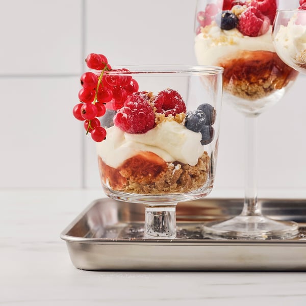 Glass dessert bowl on tray, featuring layered fruits and cream, showcasing versatility for serving sweet treats.