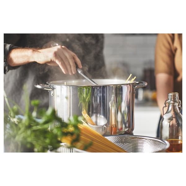 Cooking scene with stainless steel pots, herbs, and a bottle.