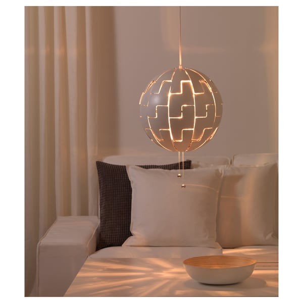 Modern hanging lamp casts light patterns, adjustable brightness with strings, atop a bed with pillows.