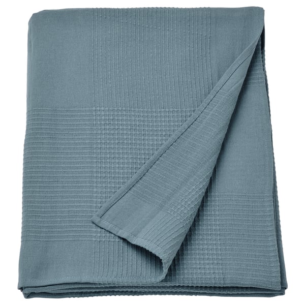 An INDIRA blue cotton bedspread, folded neatly, with a textured weave, offering warmth and comfort.