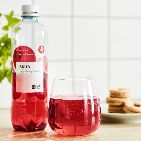 Lingonberry drink bottle with low sugar next to a glass and cookies.