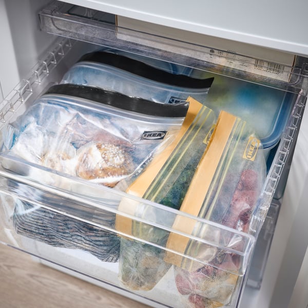 Fridge drawer filled with reusable, sealable bags storing various frozen foods.