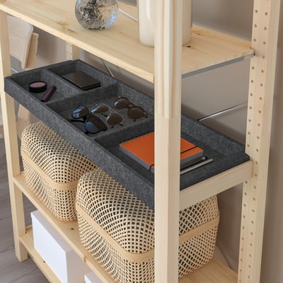 Organised storage shelves with compartments for accessories and small items, part of the IVAR system.