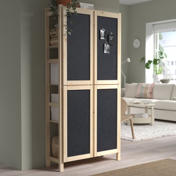 IVAR pine storage unit with felt doors holds tasks and decor in living room. Tall, natural wood finish.