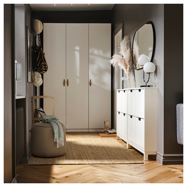 Cosy entryway with JÄRRESTAD pouffe, storage unit, and decor. Modern, neutral tones, wooden floors, round pouffe, grey and beige.