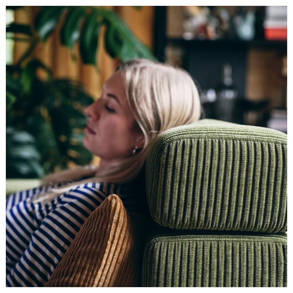 Woman relaxing on green modular sofa.
