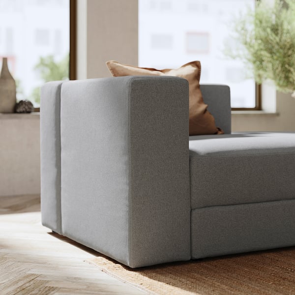 Modern grey JÄTTEBO modular sofa with wooden floor and beige pillow.