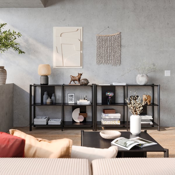 Modern living room: bookshelf, sofa, decor, abstract art, rug, metal shelf with books and vases.