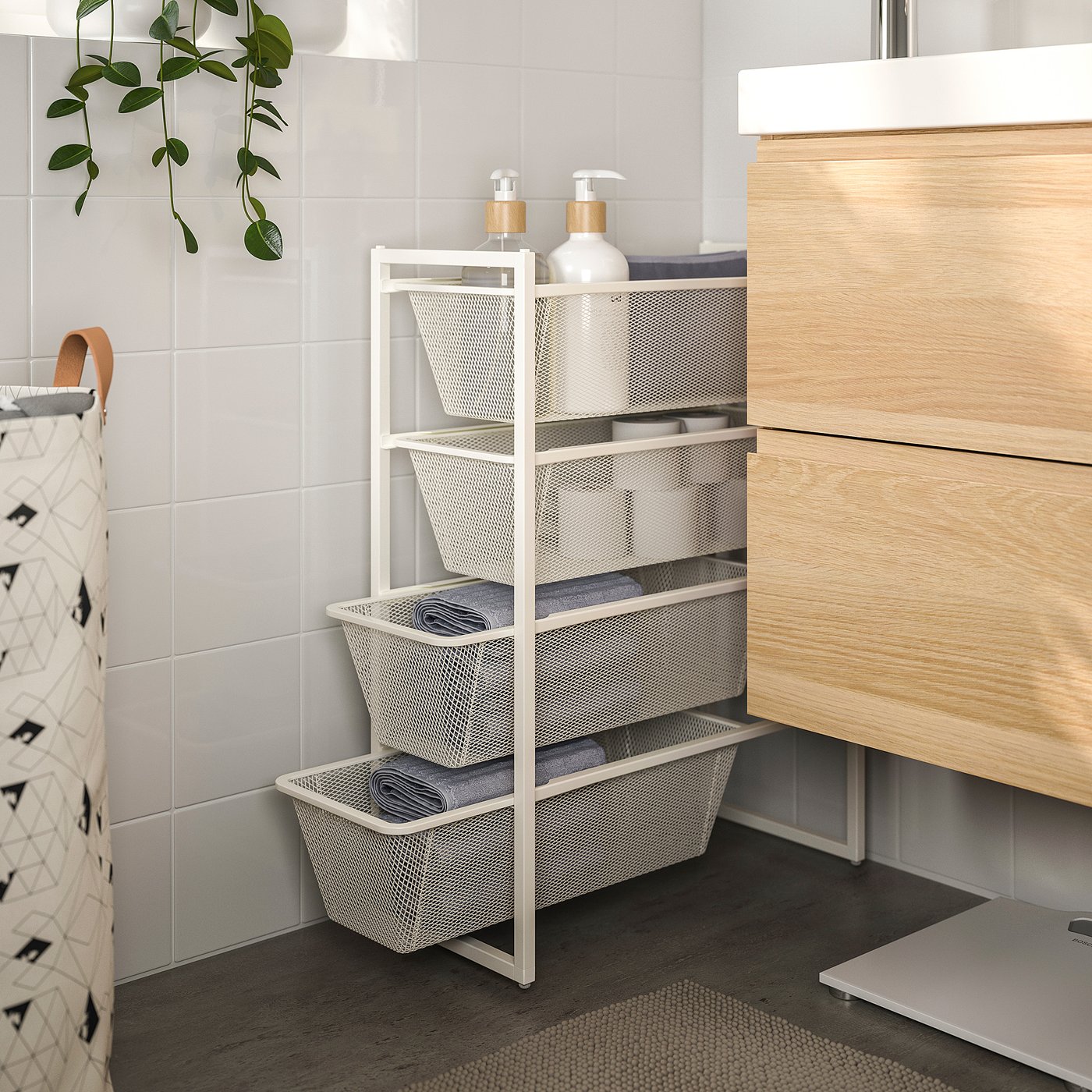 White JONAXEL metal bathroom organiser near sink, holding towels and toiletries.