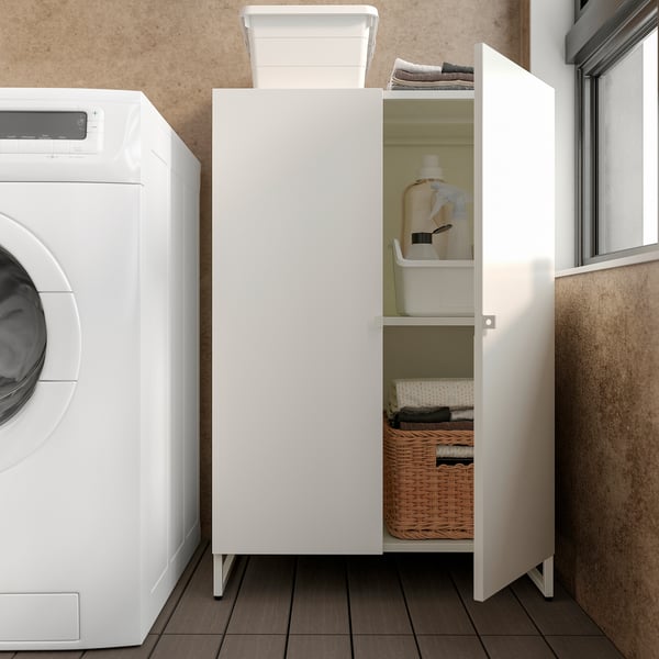 White cabinet in laundry room stores cleaning supplies, folded clothes, and wicker basket.
