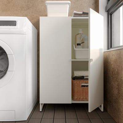 White cabinet in laundry room stores cleaning supplies, folded clothes, and wicker basket.