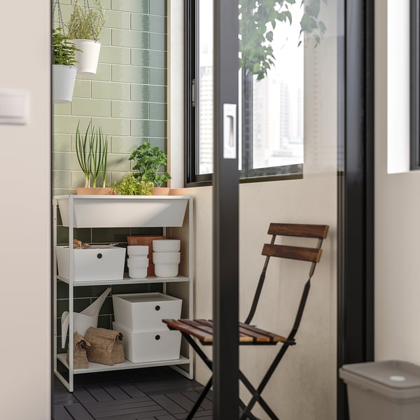 JOSTEIN white metal storage unit with shelves holds potted plants and white bins, used indoors near window.