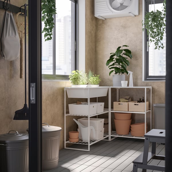 Balcony with JOSTEIN shelves holding plants and tools, metal frame, window light.