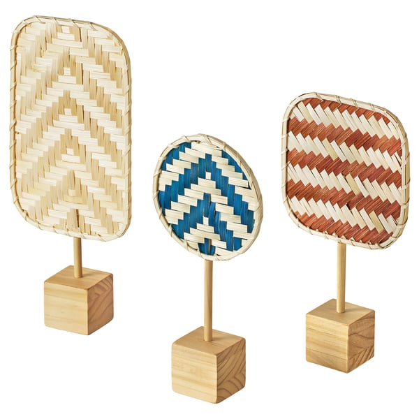 Three handmade bamboo decorations in beige, blue, and red. Rectangular, oval, and square shapes. Standing on wooden bases.