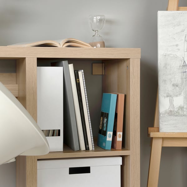 Bookshelf with various books, boxes, and a lamp. Organised and neat storage.