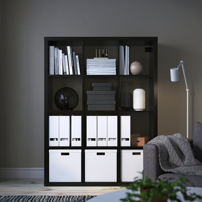 KALLAX black shelf - tall, multi-compartment, holding books & decor.