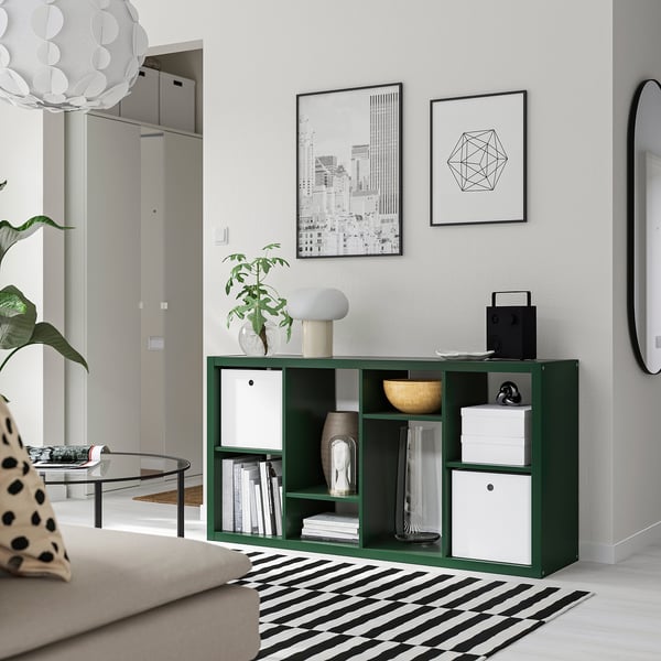 Green KALLAX shelving unit in living room, filled with items, near sofa and coffee table.