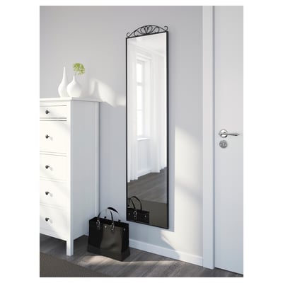Mirror on grey wall beside dresser, handbag on floor, reflects windowed room.