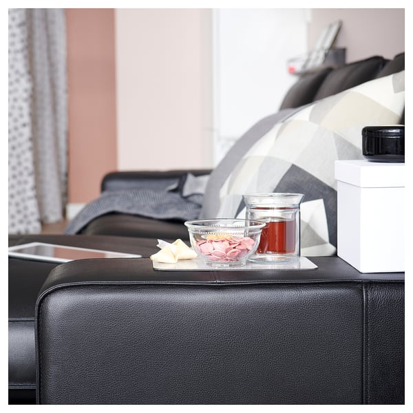 Black KIVIK sofa arm with teaset, snacks, and remote.