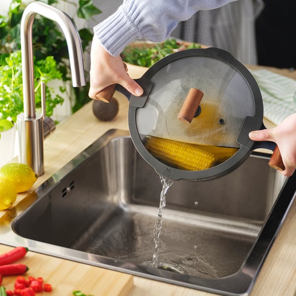 Pouring water from strainer into sink.