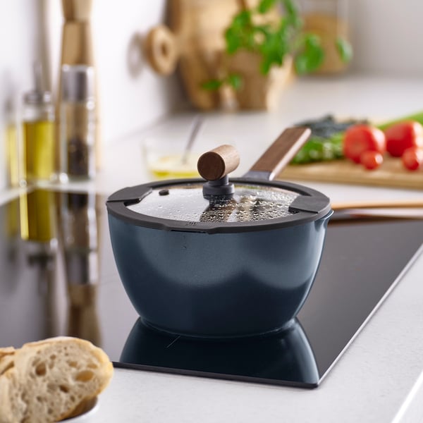 KLIPPFISK saucepan in dark blue on stove, smaller than bread loaf, with wooden handle and lid, surrounded by ingredients.