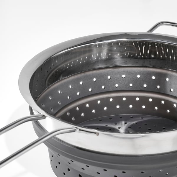 Stainless steel colander with fold-out handles and perforated base for efficient draining.