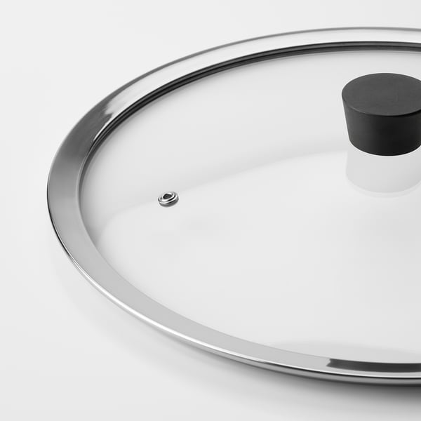 Clear glass lid with stainless steel rim, handle, and vent on a metallic base.