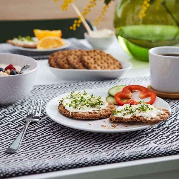 Breakfast spread with crackers, fruits, cream-topped crispbread, and coffee.