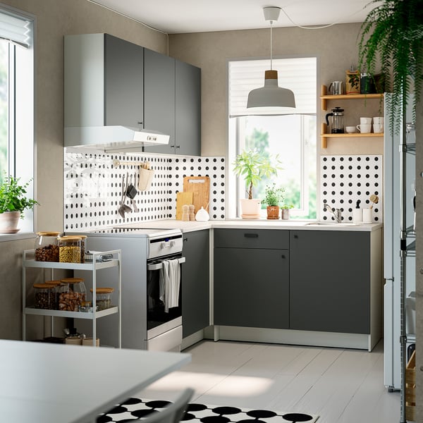 Modern l-shaped kitchen dark grey cabinets, sleek countertops, and open shelving with potted plants and coffee essentials.