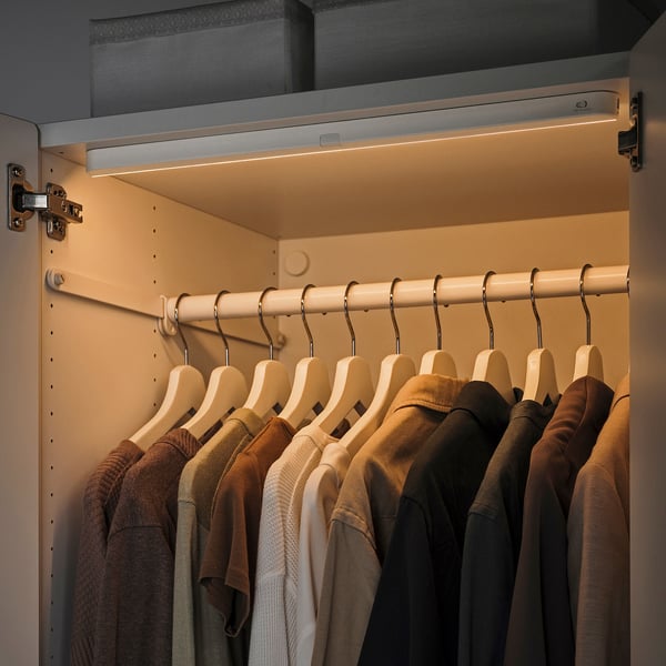 Modern closet with warm led lights. Slim, automatic sensor lights illuminate hangers and clothes.