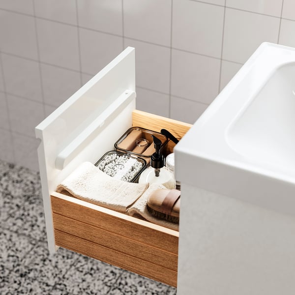 Open bathroom drawer with soft light showing toiletries and a towel.