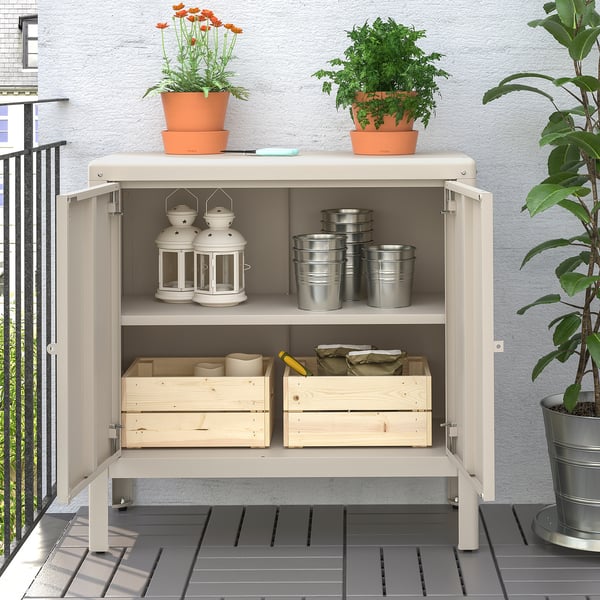 Balcony storage cabinet with potted plants, lanterns, and tools.