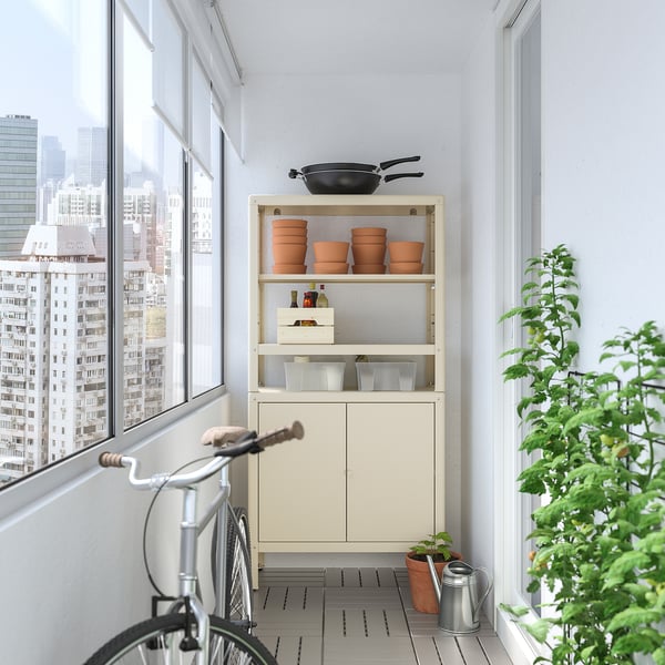 KOLBJÖRN: white storage unit with steel shelves and cabinet. Holds plant pots and bike on balcony.