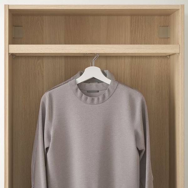 Wooden closet with hanging grey sweater on rail, visible hangers.